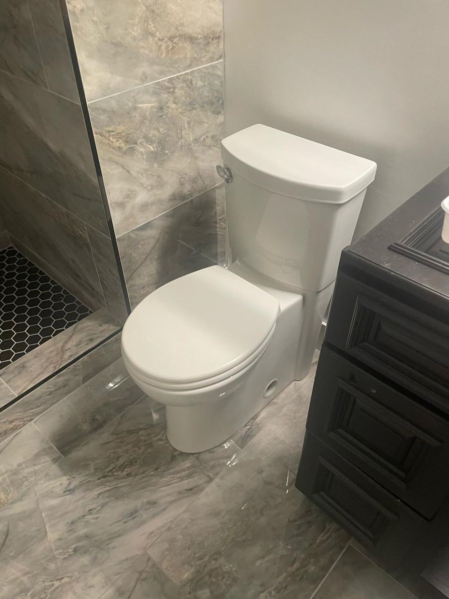 New toilet beside gray marble floor and shower glass