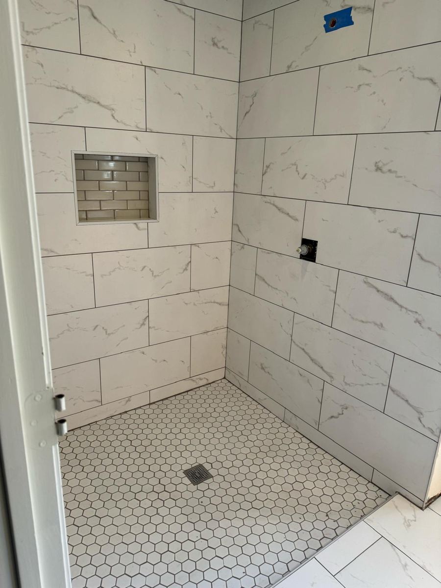 Finished white marble-look shower with niche and hexagon floor