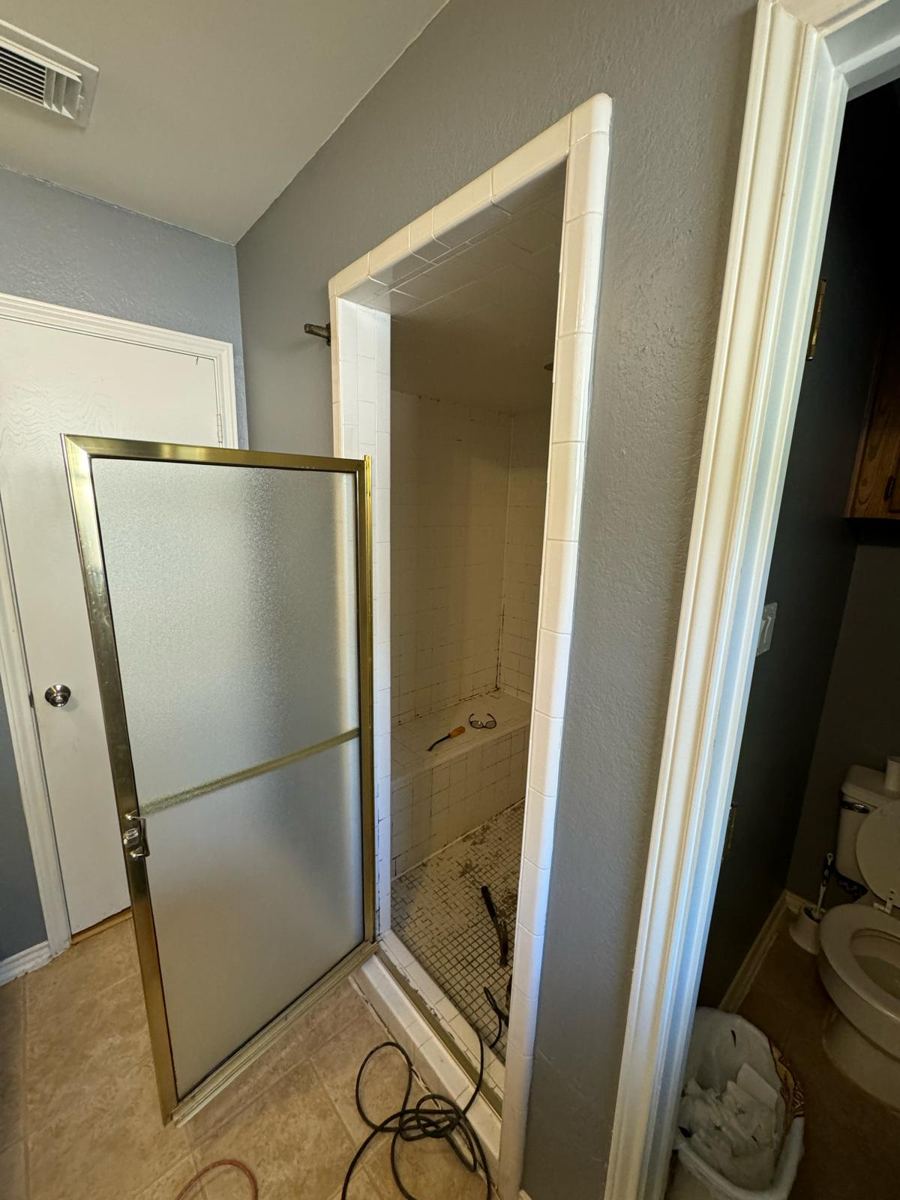 Old shower with frosted brass-framed door before remodeling