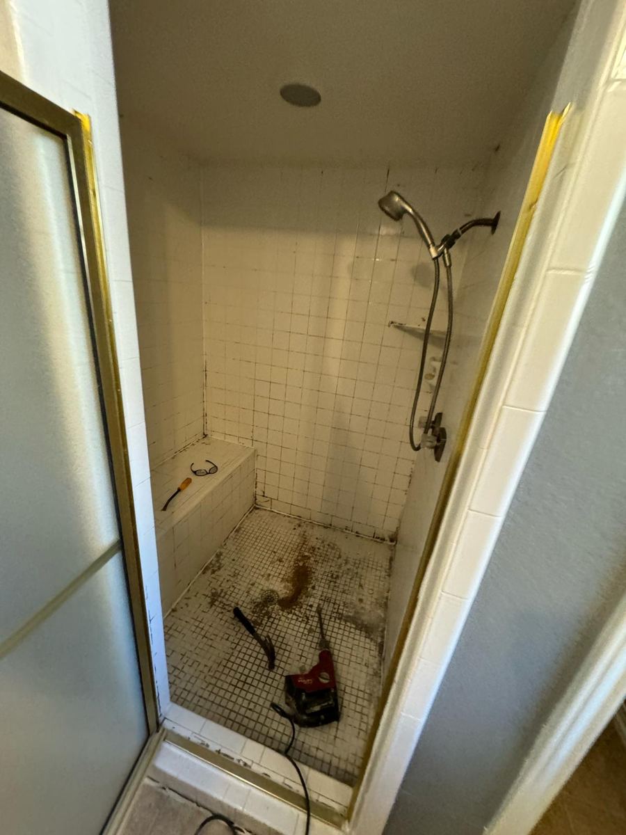 Old shower with stained floor and mildewed grout